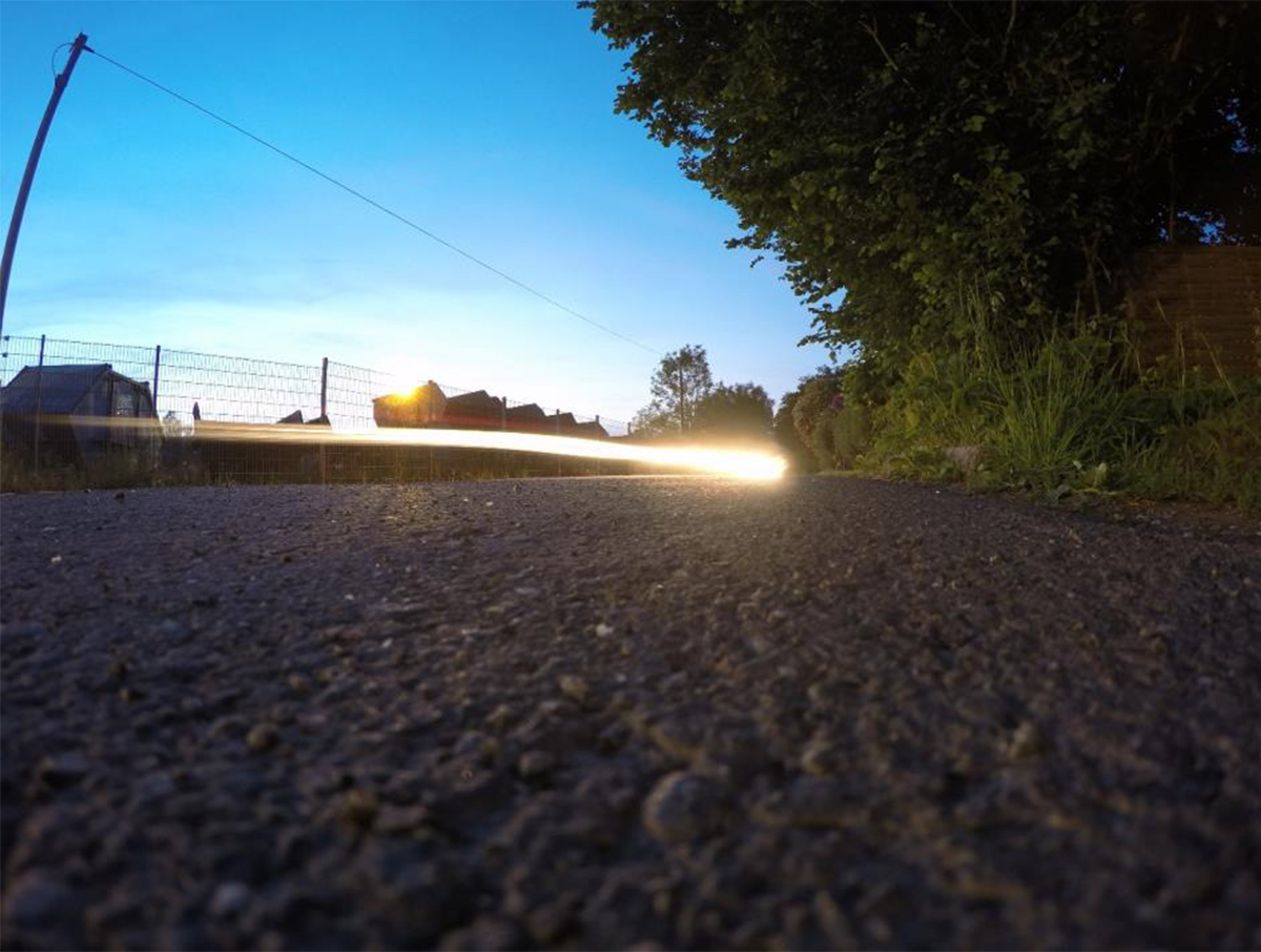 Ein vorbeifahrendes Auto hinterlässt bei Langzeitbelichtung in der Nacht einen Lichtschweif