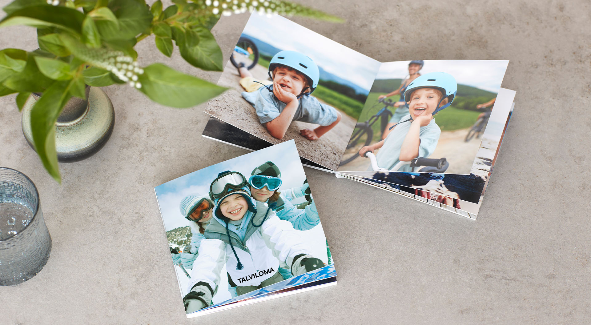 Pöydällä kaksi kuvakirjasta, joissa lomakuvia